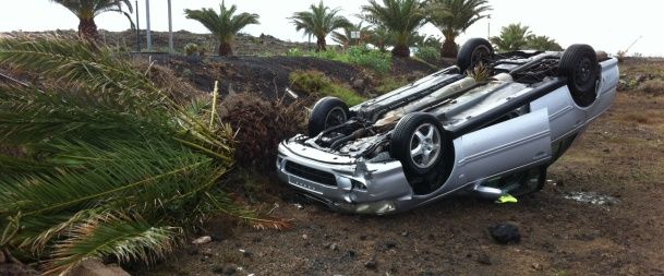 Una conductora huye tras saltarse la mediana, arrancar una palmera y volcar en Costa Teguise