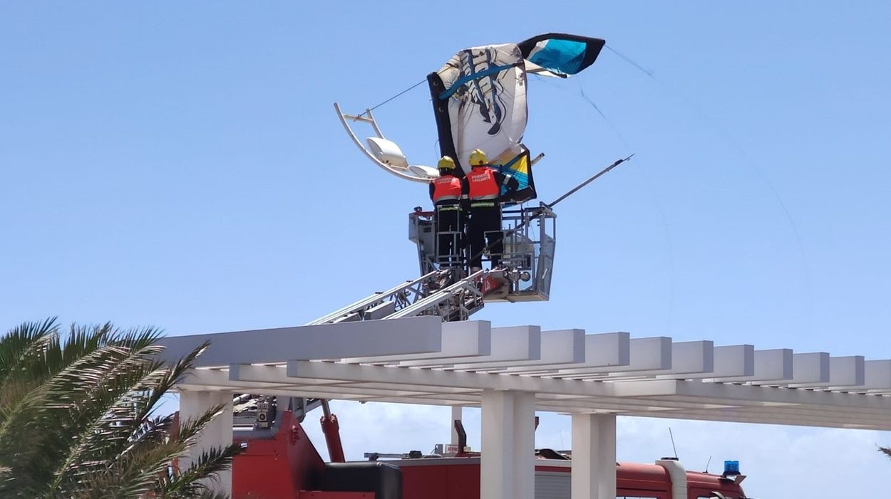 Bomberos desenganchando una cometa de kitesurf de una farola en Playa Honda