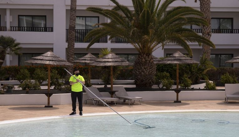 El socorrista del hotel limpiaba la piscina esperando la llegada de los primeros clientes El socorrista del hotel limpiaba la piscina esperando la llegada de los primeros clientes