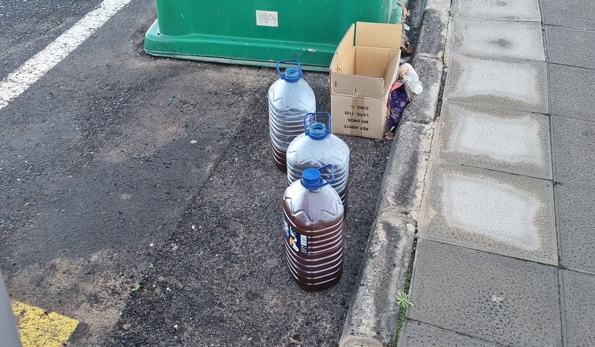 Imagen de garrafas con aceite usado junto a contenedores de reciclaje