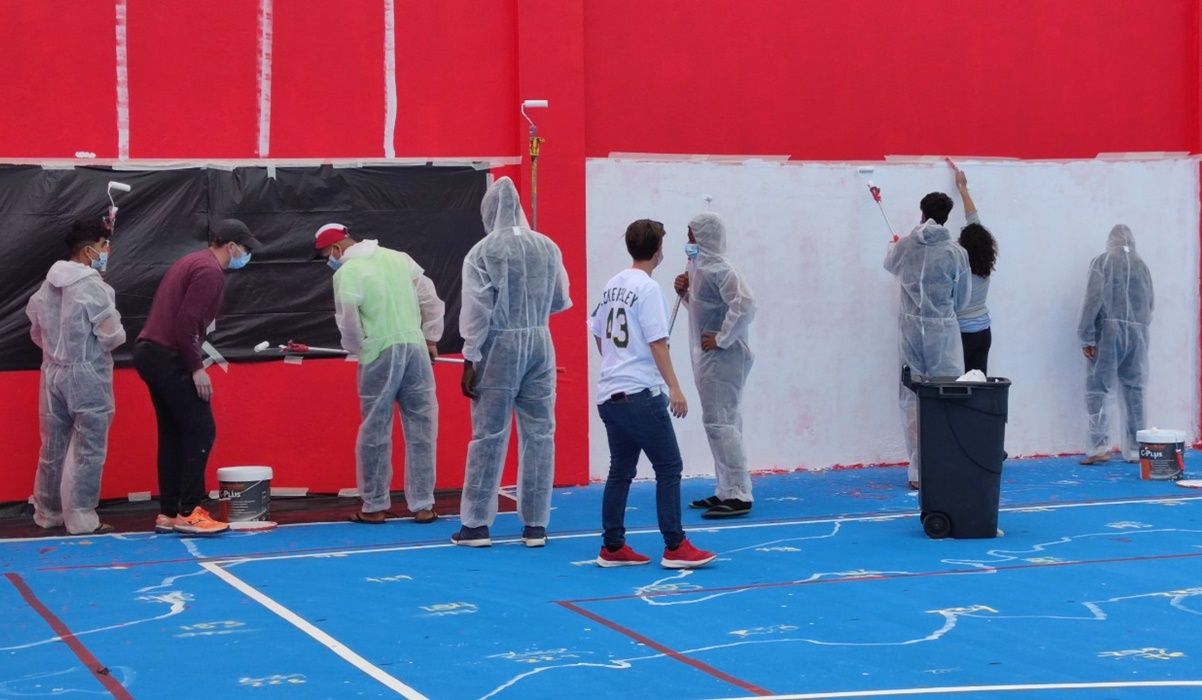Jóvenes migrantes realizando el mural