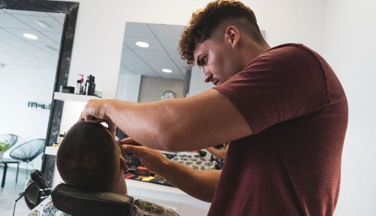 Nahuel atendiendo a un cliente en la barbería, en Costa Teguise