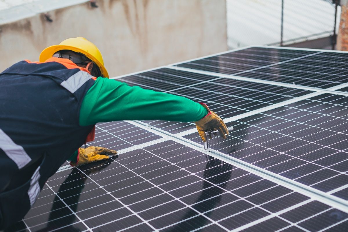 Un trabajador instala una placa fotovoltaica. Productividad.