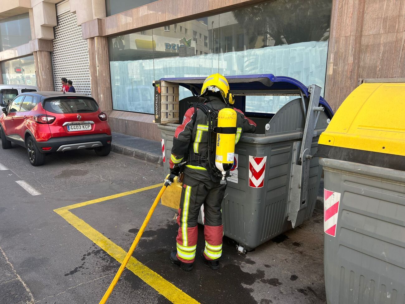 Los bomberos apagando el fuego de un contenedor