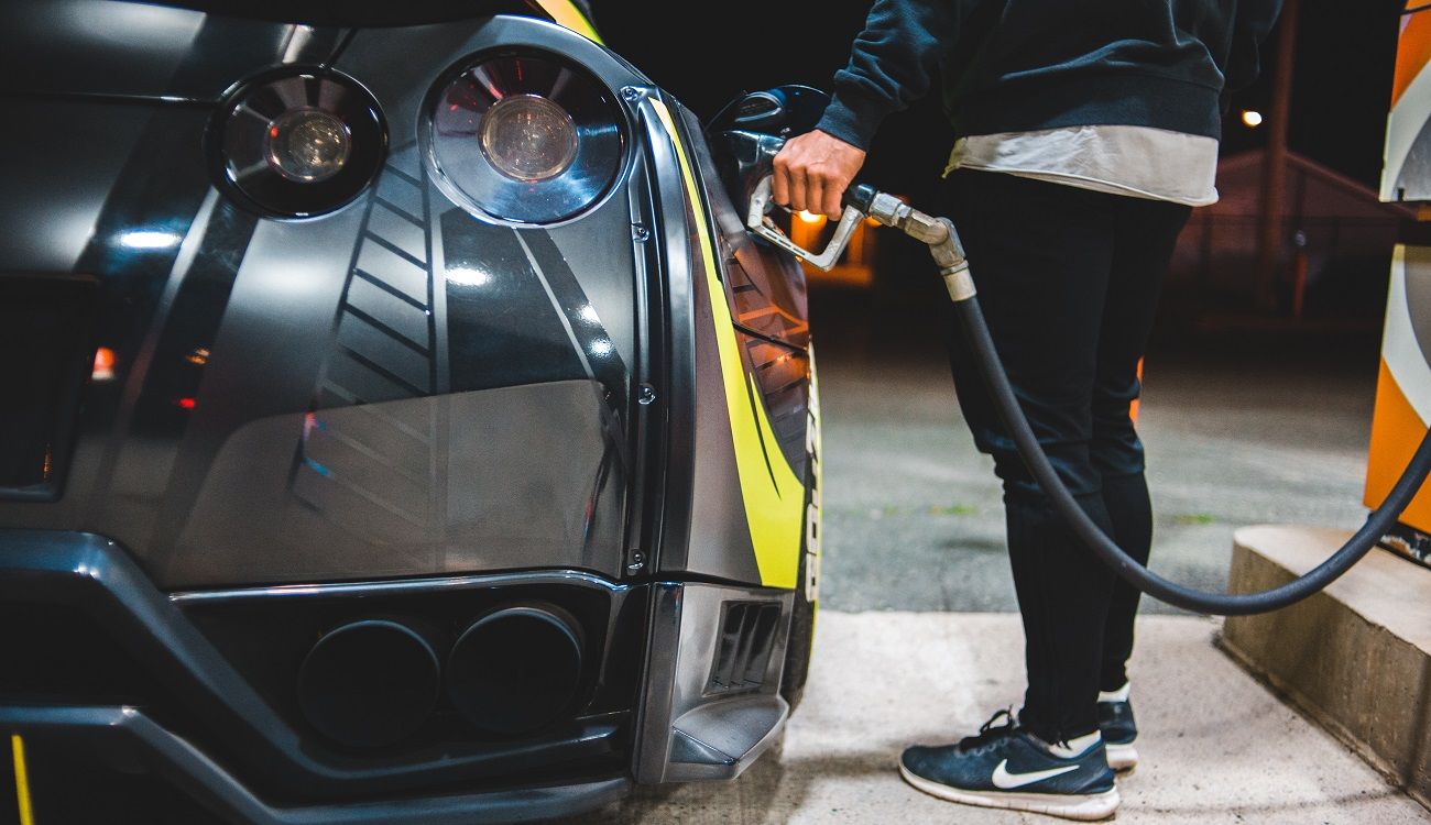 Una persona repostando el tanque del coche en una gasolinera