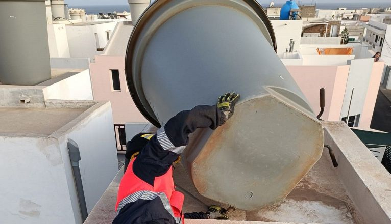 Los bomberos colocan un tanque de agua a punto de caer