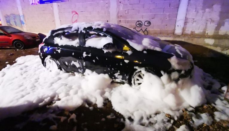 El vehículo envuelto en espuma tras el incendio