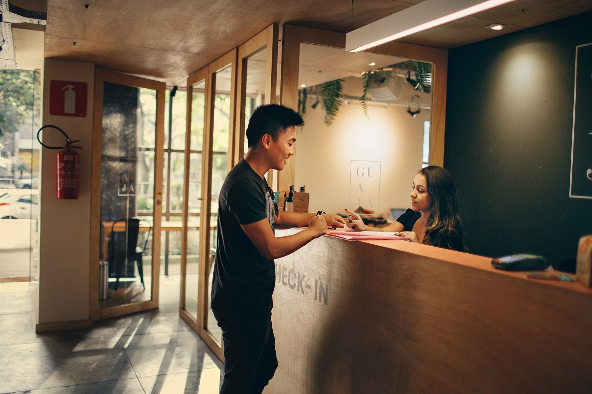 Empleada de la recepción de un hotel atendiendo a un cliente