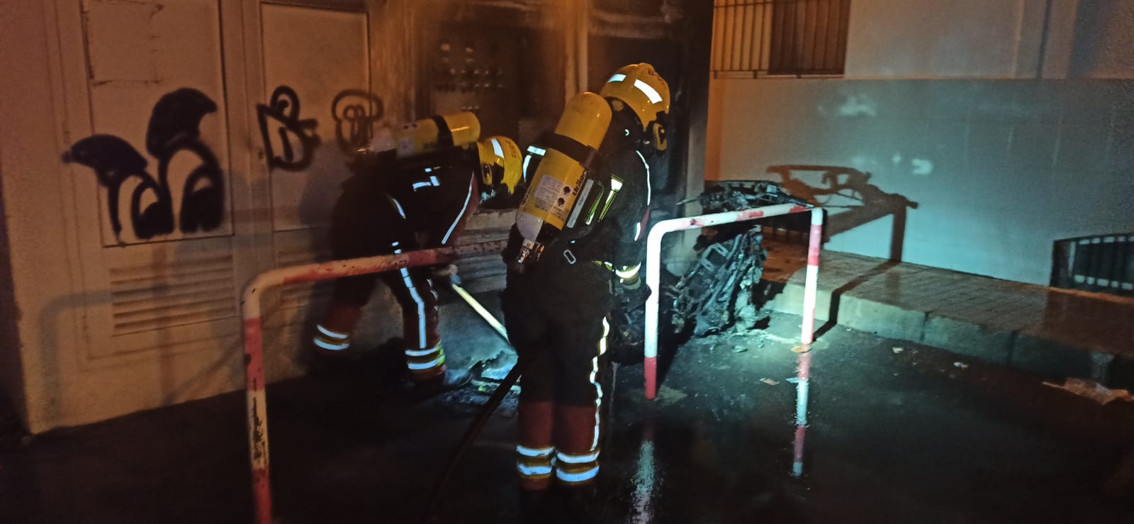 Bomberos sofocando el fuego que afectaba a la moto