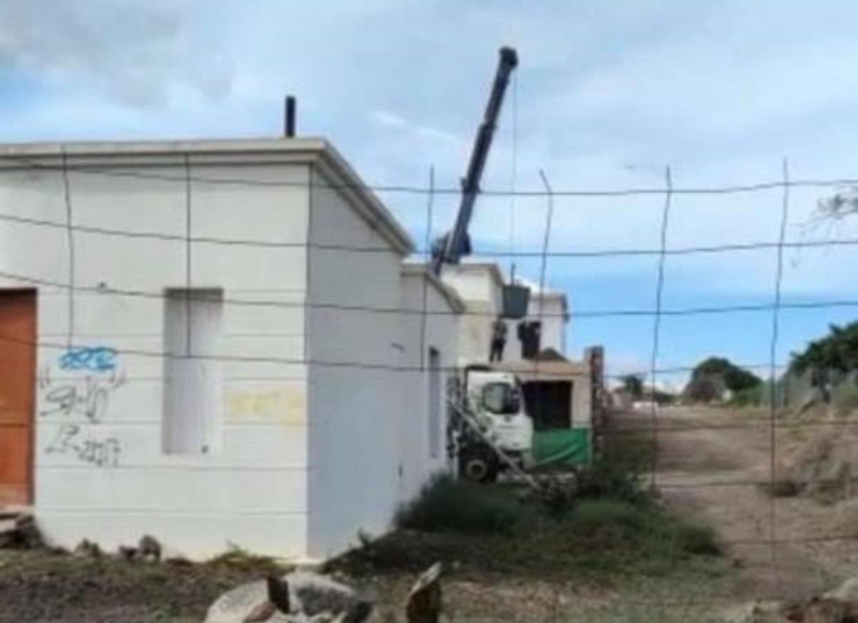 Un camión con grúa pluma descargando un porte de bloques en una construcción abandonada en Teguise