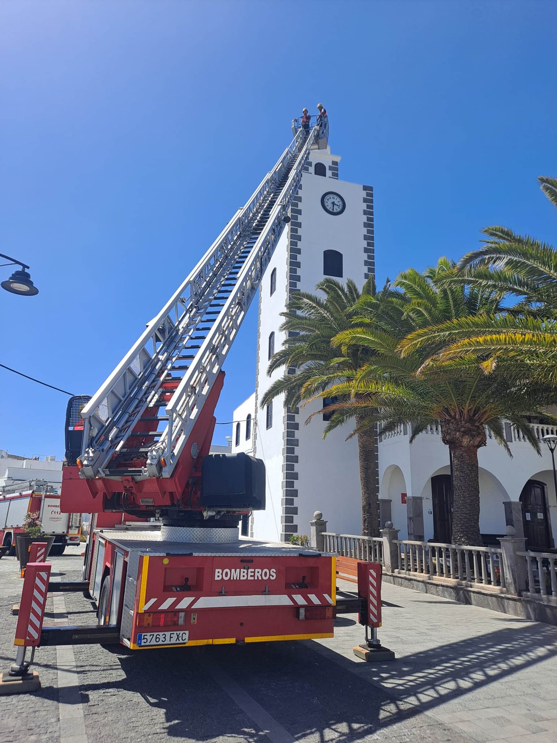 Los bomberos retirando la pieza de madera caída de la torre de la iglesia de San Bartolomé