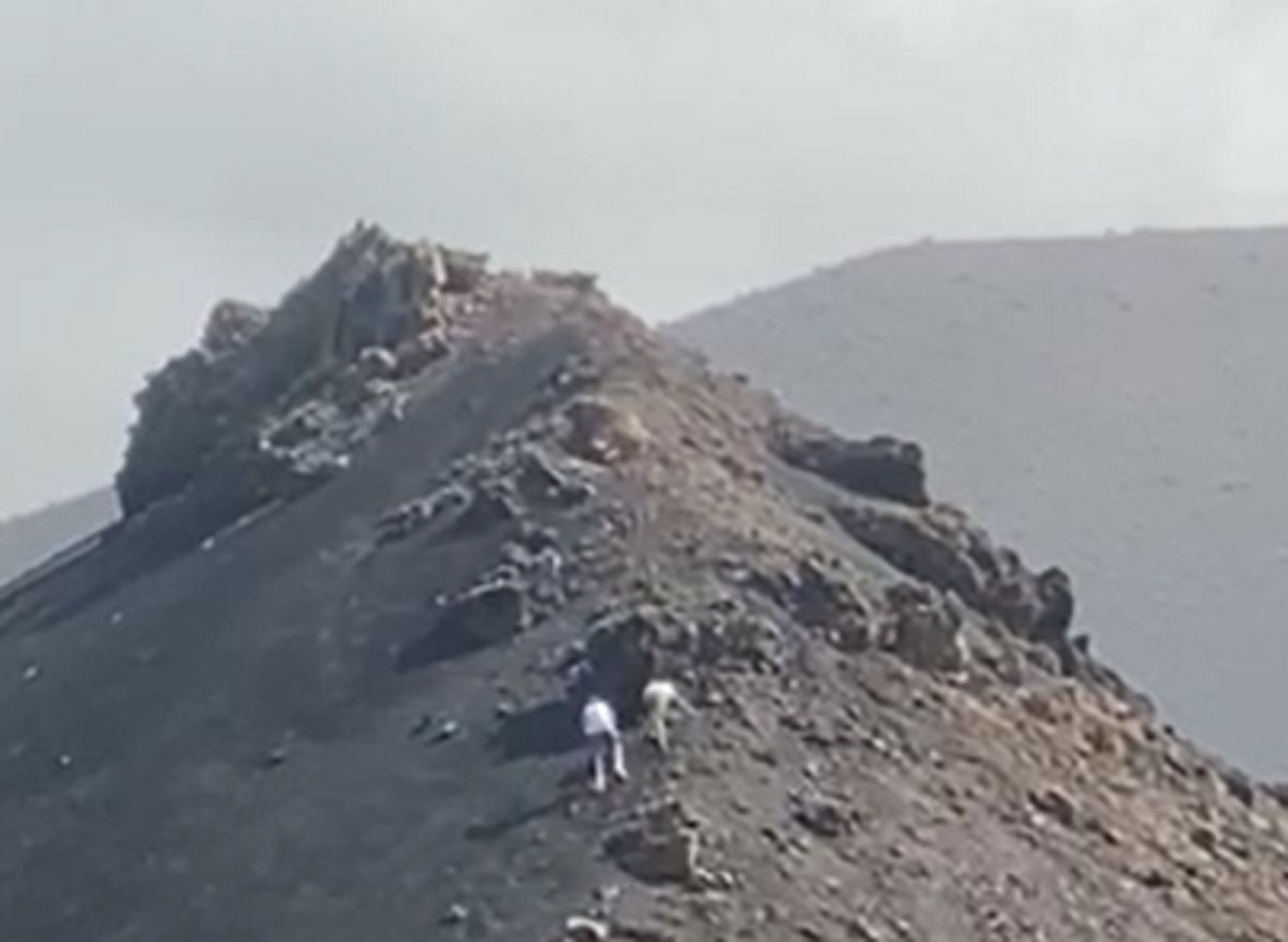 Dos turistas se salen del sendero y escalan las laderas de un volcán de este espacio protegido de Lanzarote