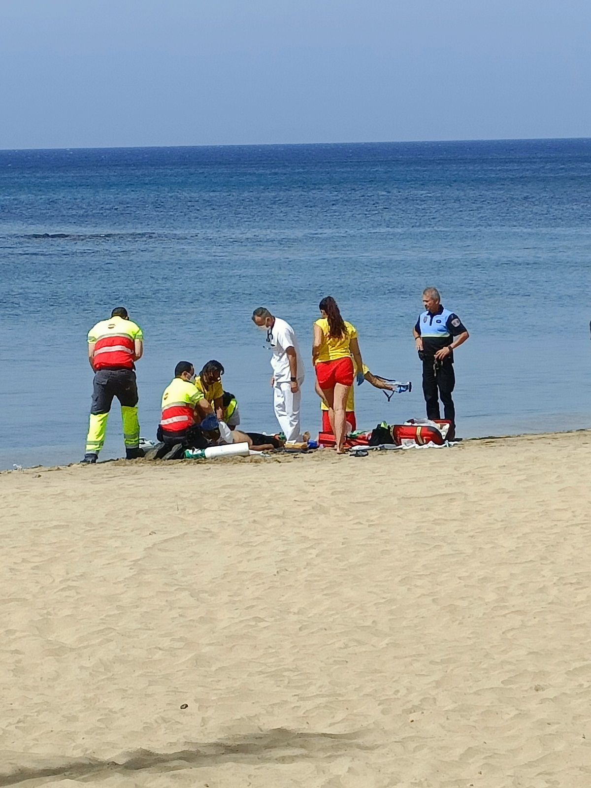 Socorristas, Policía Local y personal sanitario en el momento del rescate en la Playa del Reducto (Foto: La Voz)