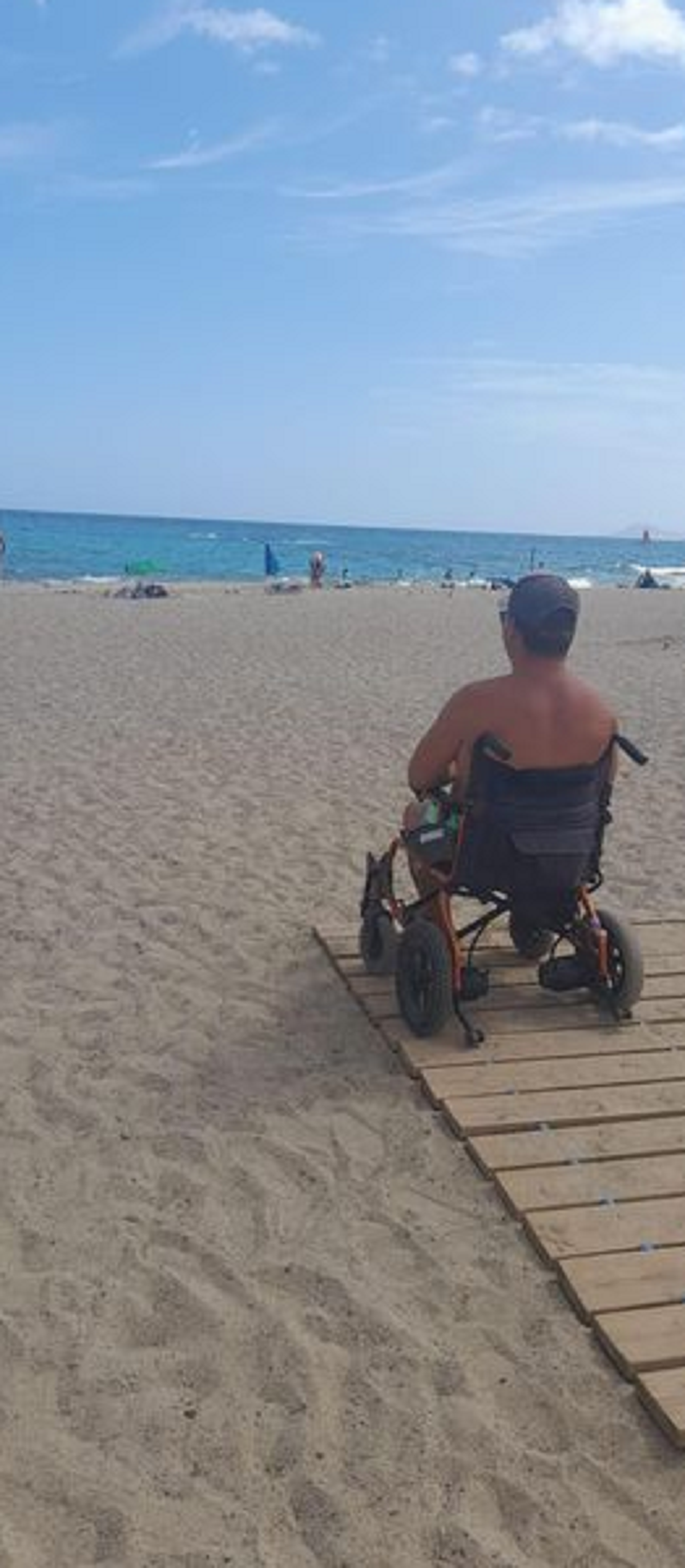 El hombre en su silla de ruedas mirando al mar en la playa del camping de Papagayo