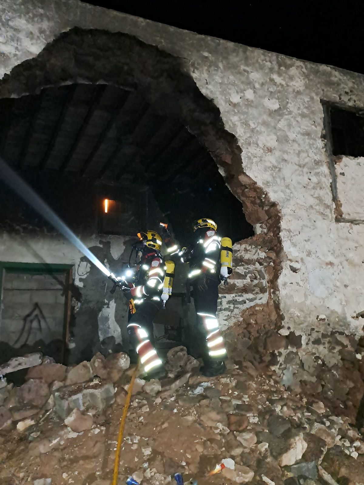 Los bomberos apagando el incendio en el techo de la casa abandonada en San Bartolomé