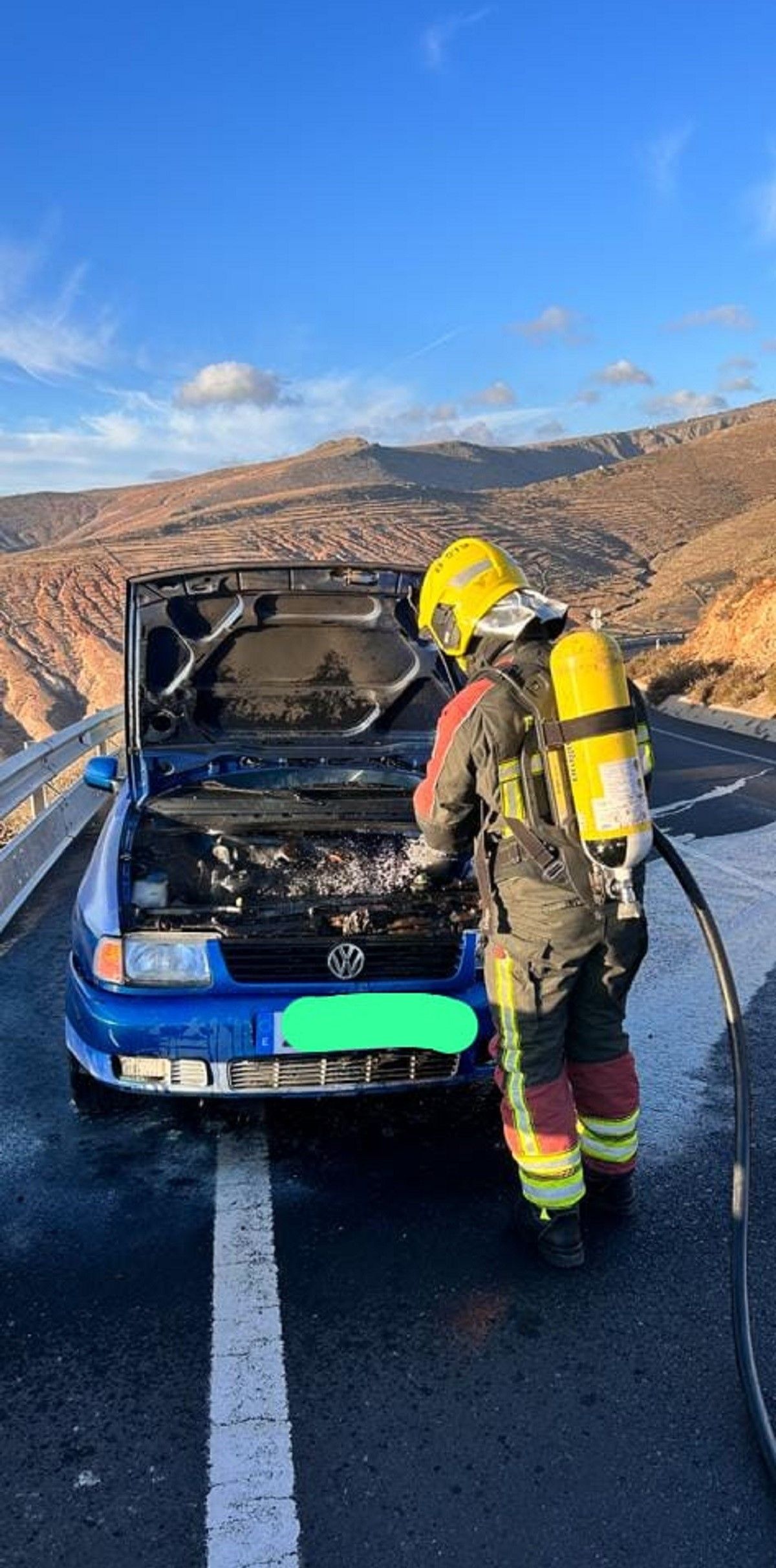 Los bomberos refrigerando el motor del vehículo en la carretera LZ-10