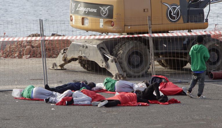 Varias personas migrantes duermen en el suelo del muelle de Puerto Naos ante la falta de recursos. Foto: José Luis Carrasco.