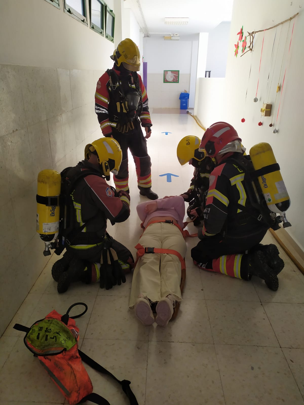 Los bomberos durante el simulacro con la persona que se encontraba en el interior del centro