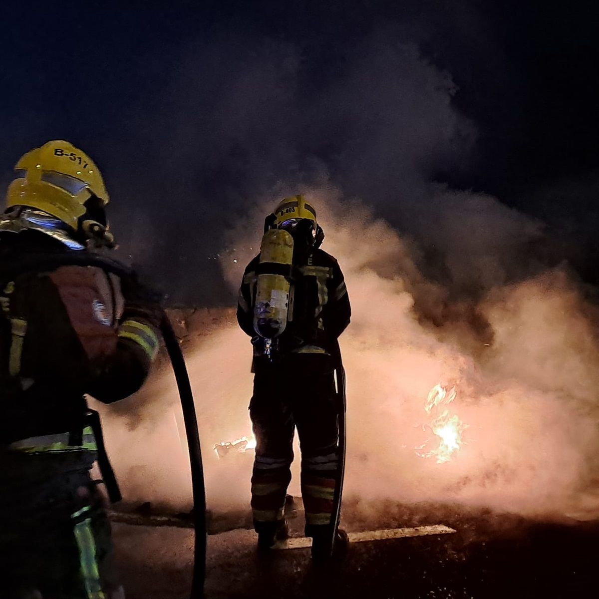 Los bomberos apagando el incendio en los dos contenedores