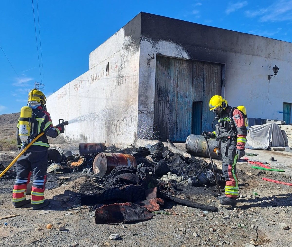 Los bomberos apagando el fuego en el exterior de la nave en Playa Honda