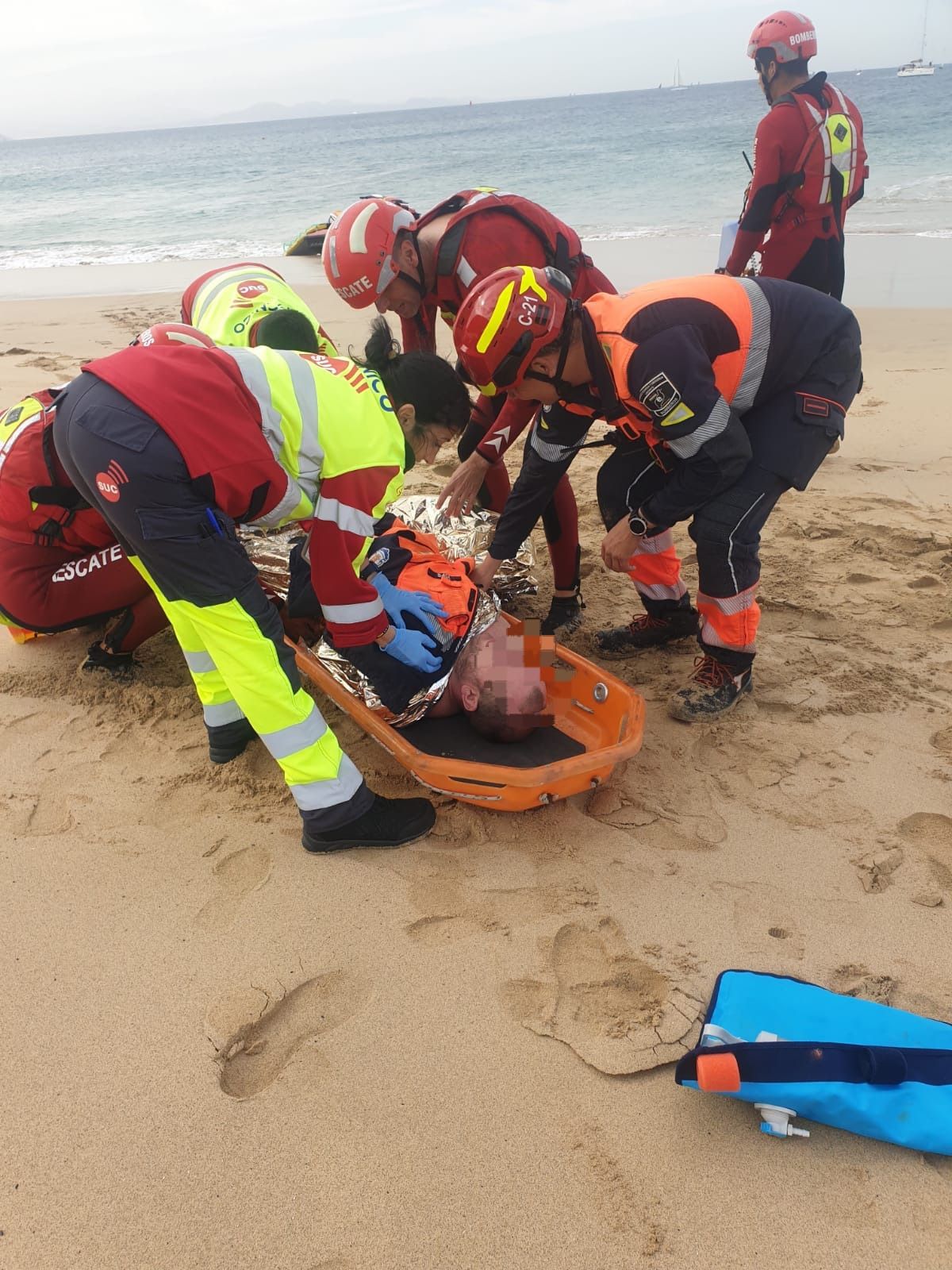 Los efectivos de emergencia y ambulancia auxiliando al accidentado en la orilla de la playa