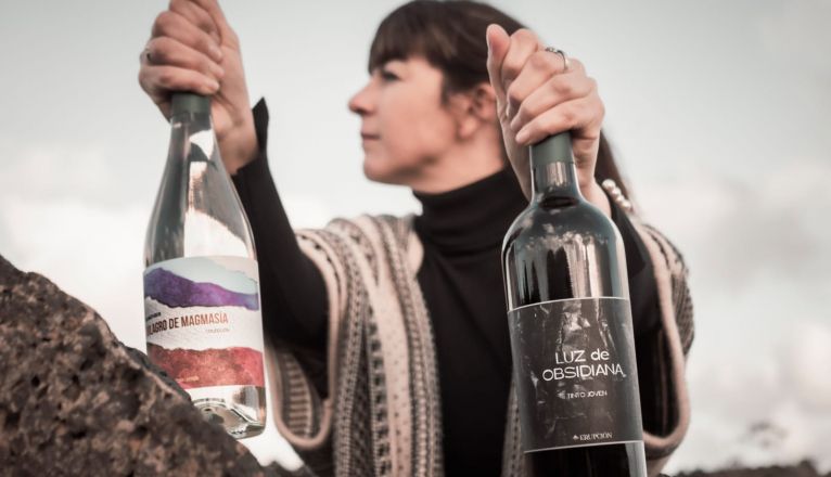 López sostiene dos botellas de sus vinos