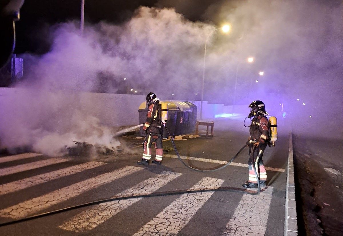 Los bomberos apagando el incendio del contenedor