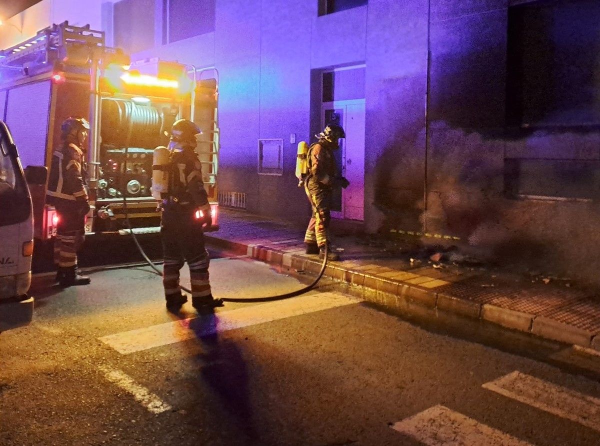 Los bomberos apagando el incendio en la vía pública