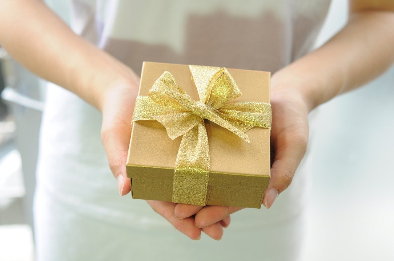 Una mujer sostiene un regalo. Comercio.