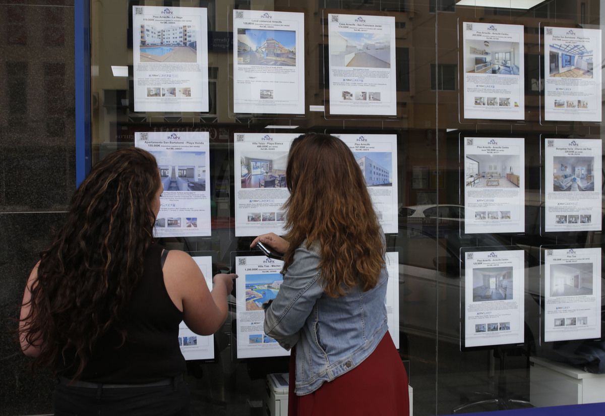 Dos jóvenes comparan ofertas inmobiliarias. Hipotecas.