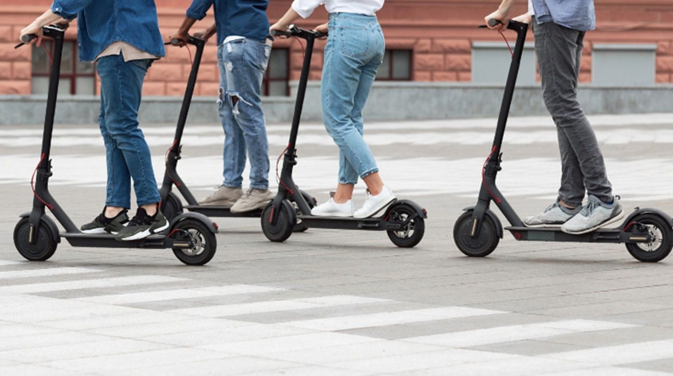 Varios jóvenes se desplazan en patinete eléctrico. Transporte.