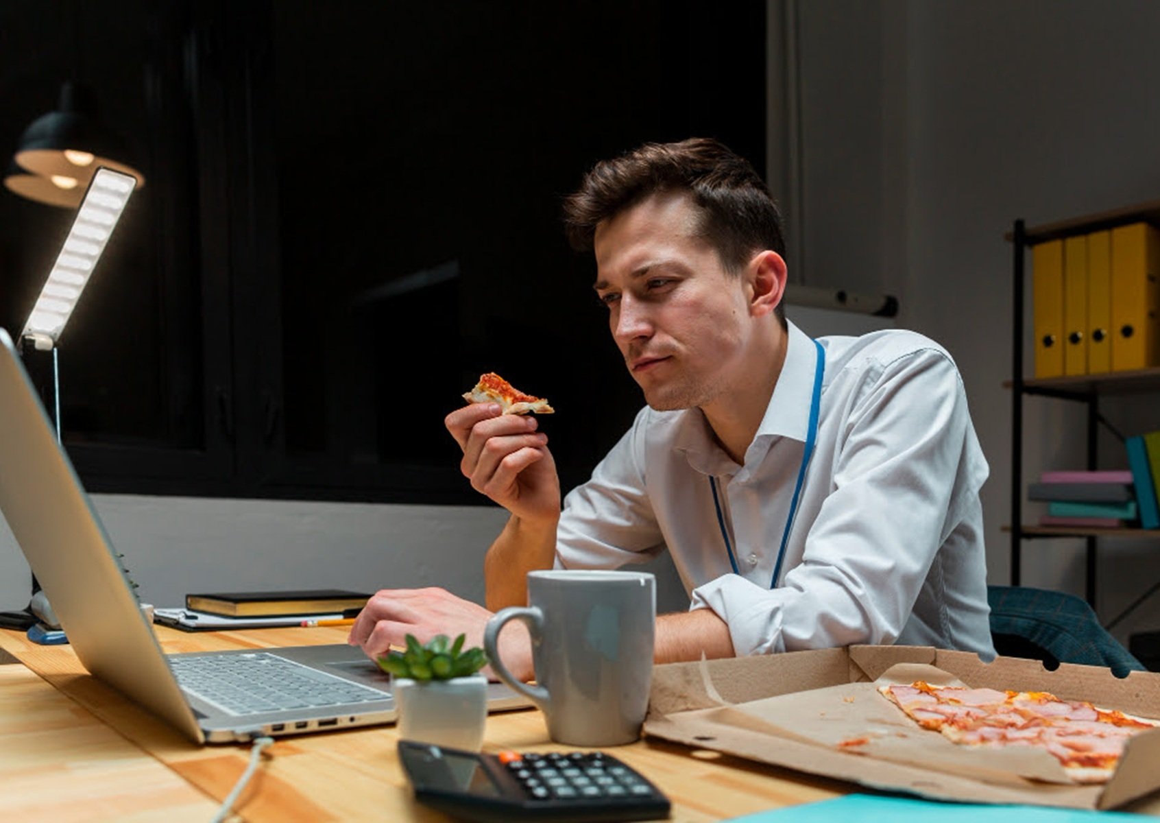 Un trabajador come frente al ordenador.