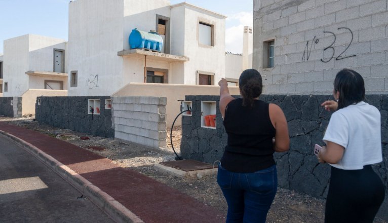 Two neighbors point to one of the unfinished homes. Photo: Juan Mateos.