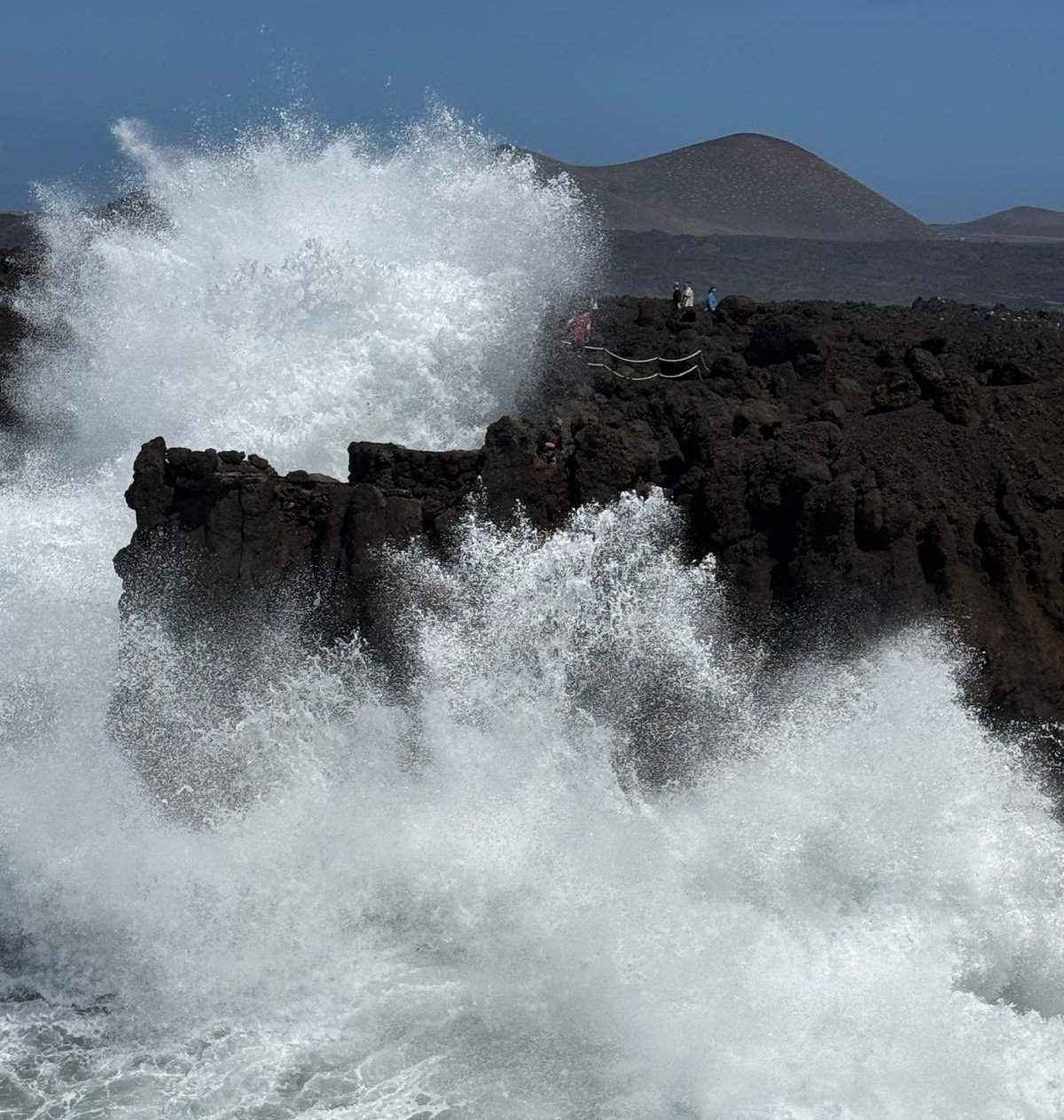 Turistas acercándose a las olas en Los Hervideros