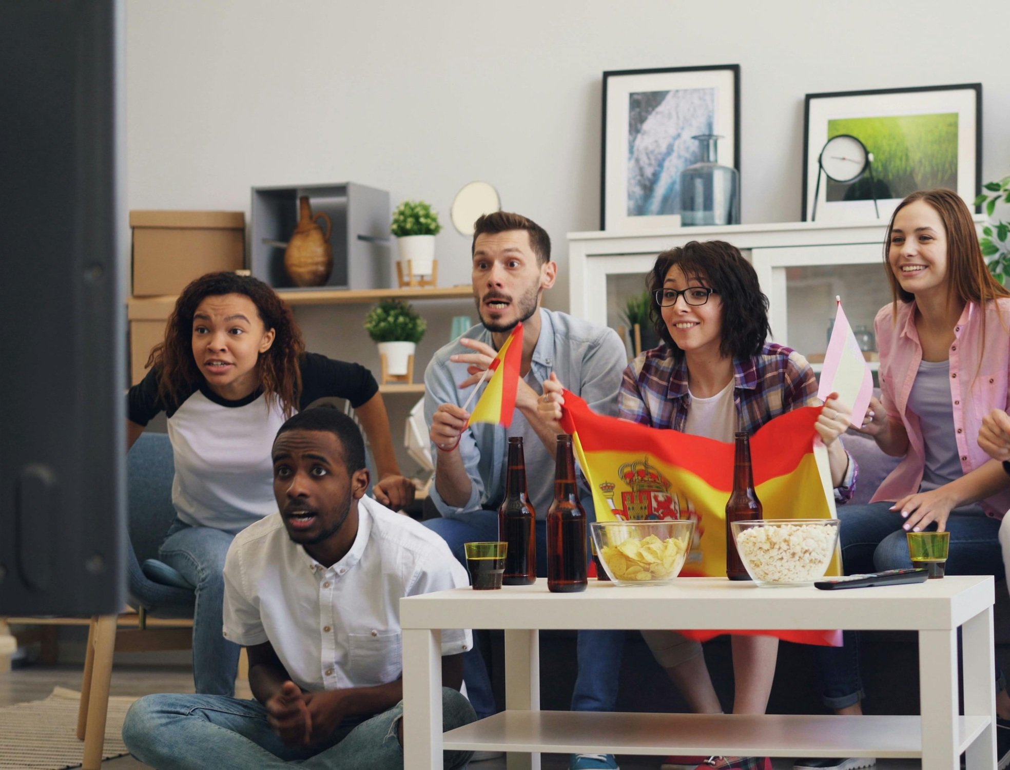 Jóvenes viendo un partido de España en la televisión. supermercados.