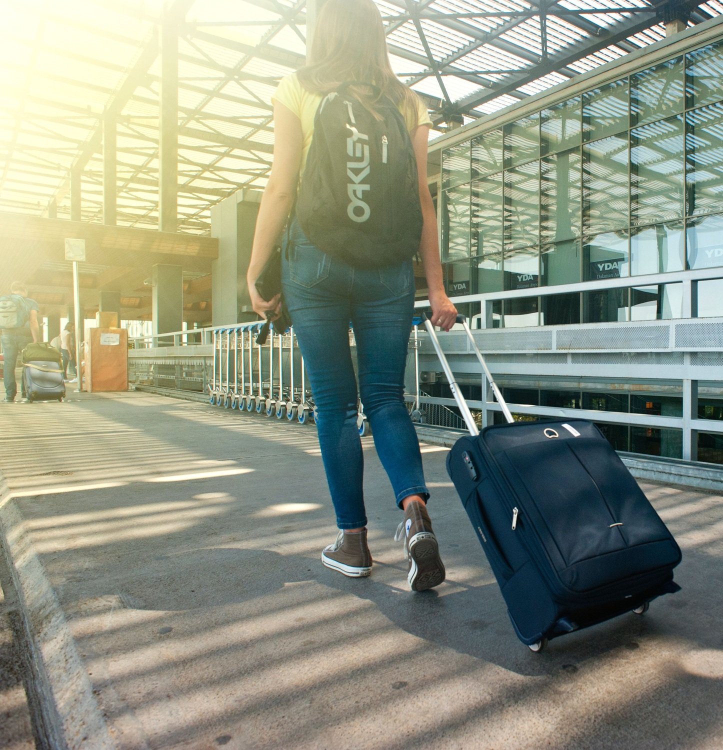 Una mujer se dirige a un aeropuerto con mochila y trolley Una mujer se dirige a un aeropuerto con mochila y trolley