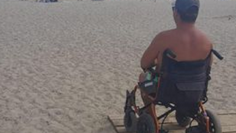 El hombre en su silla de ruedas mirando al mar en la playa del camping de Papagayo
