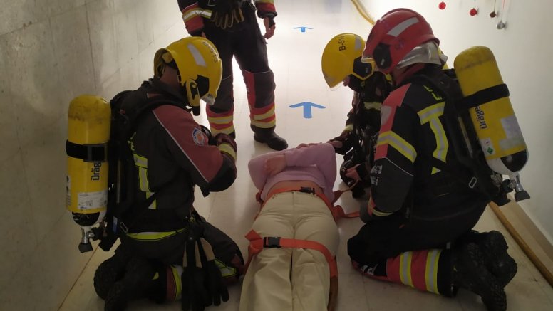 Los bomberos durante el simulacro con la persona que se encontraba en el interior del centro