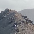 Dos turistas se salen del sendero y escalan las laderas de un volcán de este espacio protegido de Lanzarote
