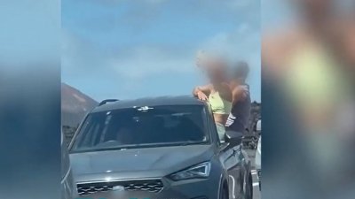 Tres jóvenes con medio cuerpo fuera del vehículo  en una carretera de Lanzarote