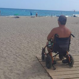 El hombre en su silla de ruedas mirando al mar en la playa del camping de Papagayo