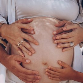 Una familia pone las manos en el vientre de una mujer embarazada. Foto: Elias Suárez (Pexels).