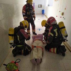 Los bomberos durante el simulacro con la persona que se encontraba en el interior del centro