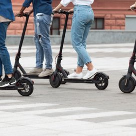 Varios jóvenes se desplazan en patinete eléctrico. Transporte.