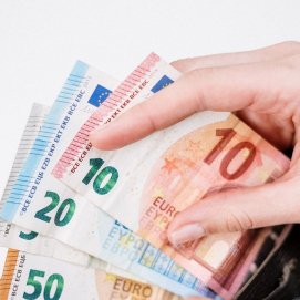 Una mujer guarda dinero en su cartera. Impuestos.