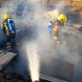 Bomberos apagando el incendio de unos corrales en Mancha Blanca