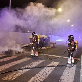 Los bomberos apagando el incendio del contenedor