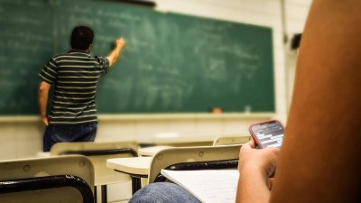 Docente dando clase mientras una estudiante usa el móvil. Foto: Pexels