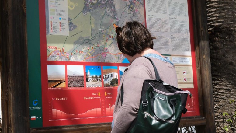 Mujer mirando el mapa de senderos de San Bartolomé