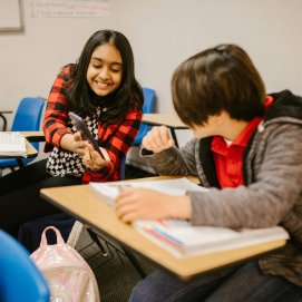 Un grupo de estudiantes usando el móvil en una clase. Foto de RDNE Stock project.